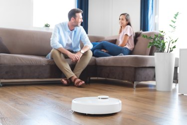 Couple in living room, robot vacuum cleaner