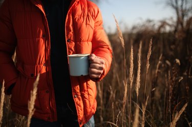 Style man in down jacket with cup of coffee