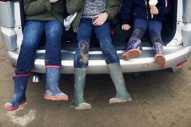 Children sitting in back of car wearing boots