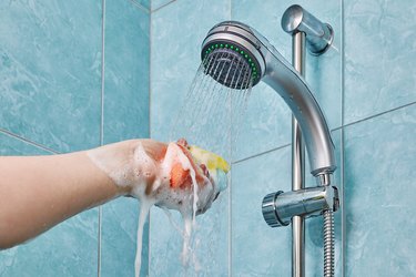 Water pouring from shower on hand with sponge