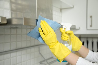 Hands in gloves cleaning stove hood