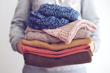 Woman holding sweaters