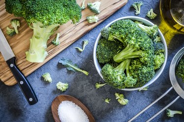 Cutting and cooking broccoli on grey textured backdrop
