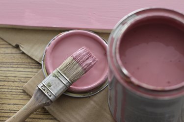 Pink paint can with brush on pink background