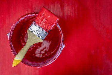 red paint can with brush on wooden plank background