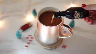 Pouring Irish cream liqueur into hot cocoa