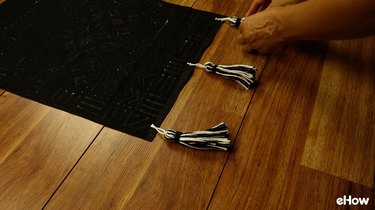 Attaching tassels to DIY mudcloth-inspired wall hanging.