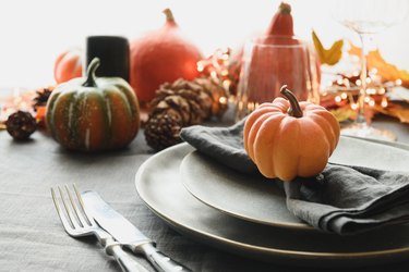 Halloween and Thanksgiving day dinner decorated fallen leaves, pumpkins, spices, grey plate.