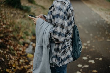 Midsection Of Woman Holding A Smartphone While Standing On Land