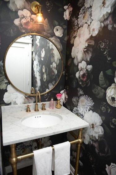 Powder room with bold floral wallpaper and scone lighting