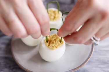 Sticking chives into egg yolk mixture to create handles