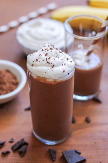 A glass with chocolate shake and whipped cream on top.