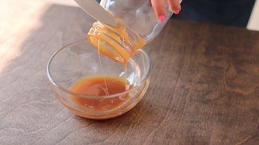 Dipping the rim of a Mason jar in caramel sauce.
