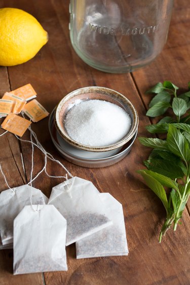 A spread of ingredients for sun brewed tea: tea bags, lemon, sugar and peppermint