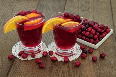 Cranberry and orange juice health drink with fresh fruit on oak background. High in vitamins, anthocyanins, and antioxidants.