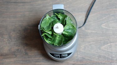 Baby spinach packed down into food processor
