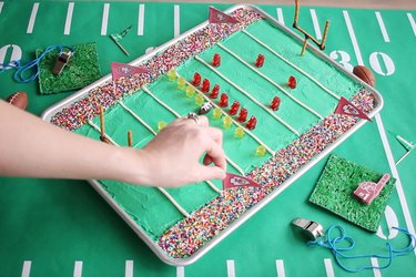 Sticking toothpick flags with team pennants into cake