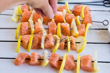 salmon kabobs being sprinkled with pepper