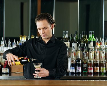 Bartender pouring cocktail behind bar