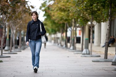 Woman walking on sidewalk in park
