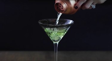straining apple martini into martini glass