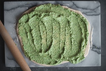 Spread the pesto all the way to the edges of the dough.