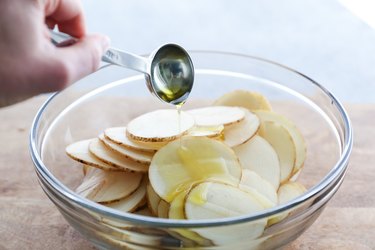 Olive oil being poured over potato slices