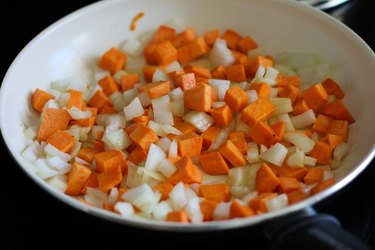 Chopped onion and sweet potato in a skillet.