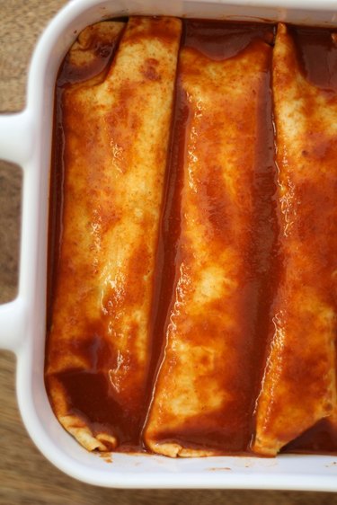 Casserole dish with stuffed tortillas and sauce.