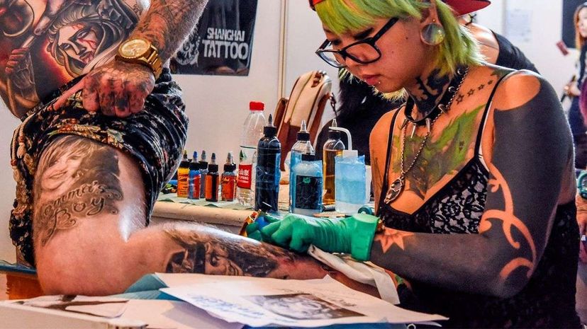 A tattooist sporting a blackout tattoo on her left arm makes a tattoo during the China Tattoo Convention 2015. ChinaFotoPress/ChinaFotoPress via Getty Images